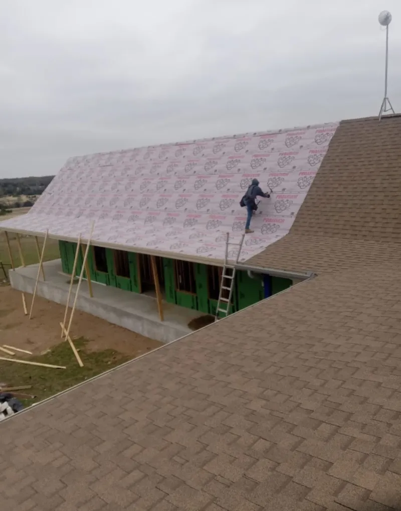 Worker preparing underlayment for a metal roof installation in East Hempfield